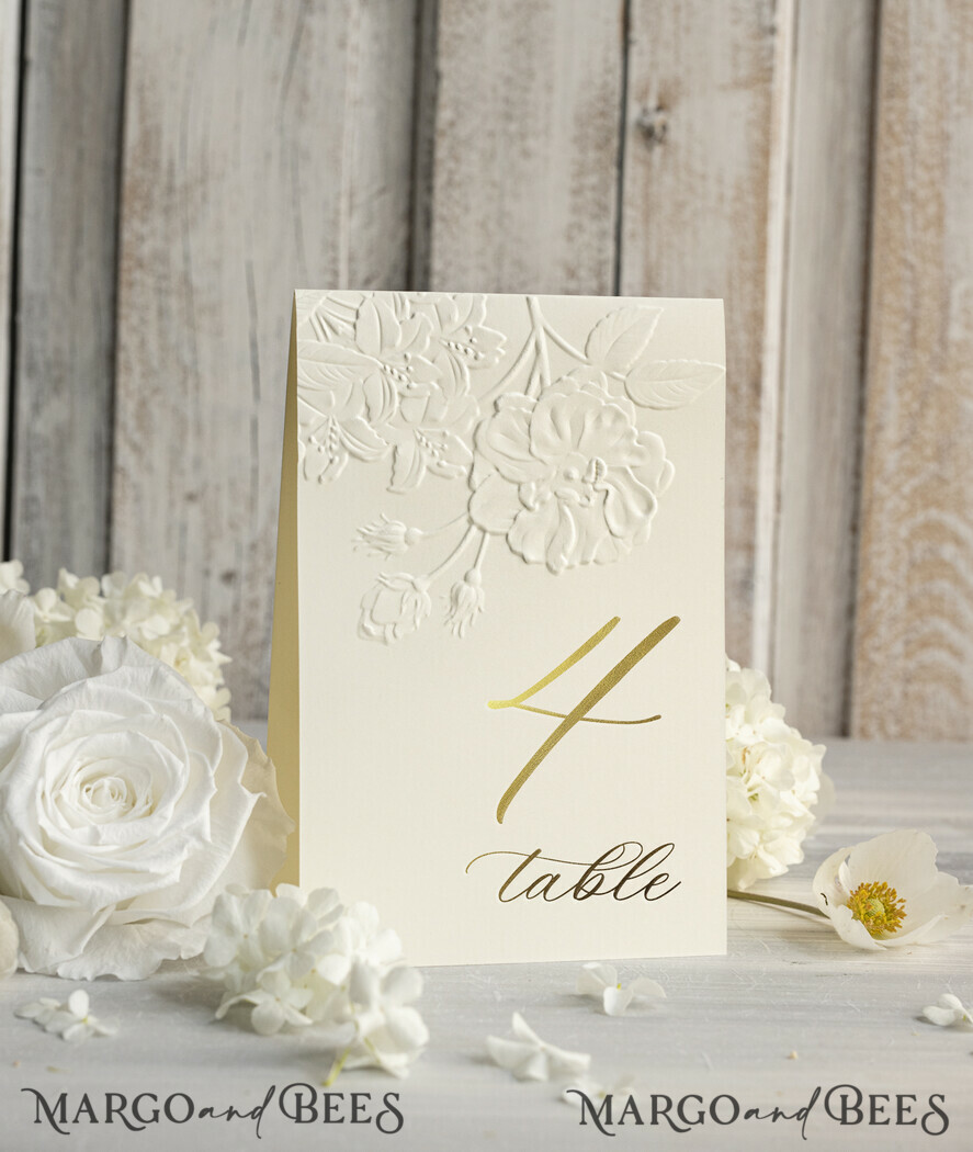 TISCHDEKORATIONSCHILDER   Glitzer Elegante goldene Hochzeits-Tischnummernkarten mit geprägtem floralen Design, elfenbeinerne strukturierte Papiere, gefalteter Zeltstil, klassische Schriftart, luxuriöse Empfangsdekoration