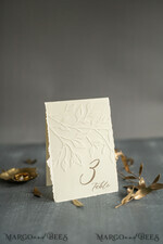 TISCHDEKORATIONSCHILDER   Glitzer Elegante Hochzeitstischnummernkärtchen mit geprägtem Blumenmuster – Elfenbeinfarbene strukturierte Papiere, gefaltete Zeltform, klassische Schriftart, luxuriöse Empfangsdekoration4